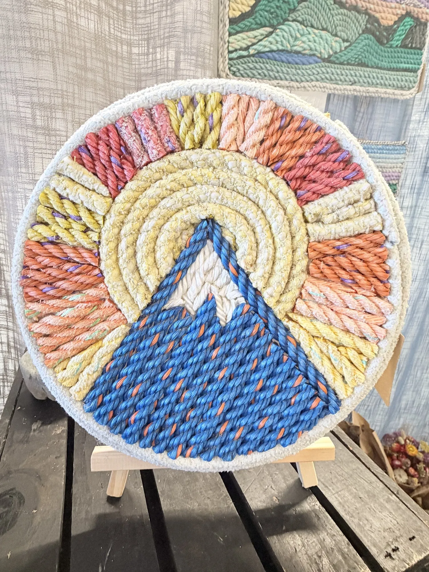 Round rope wall art of Sugarloaf mountain in navy under a yellow sun and coral, pink, and yellow rays